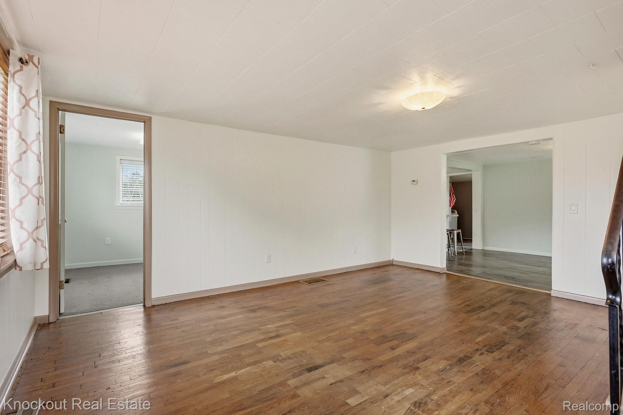 8771 Van Cleve Road Vassar, MI 48768 - Photo 11 of 44 Hardwood flooring, recessed lighting, white wall paneling, white walls, and a wood-frame doorway
