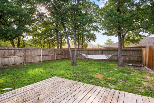 a view of a backyard with wooden fence and a large tree