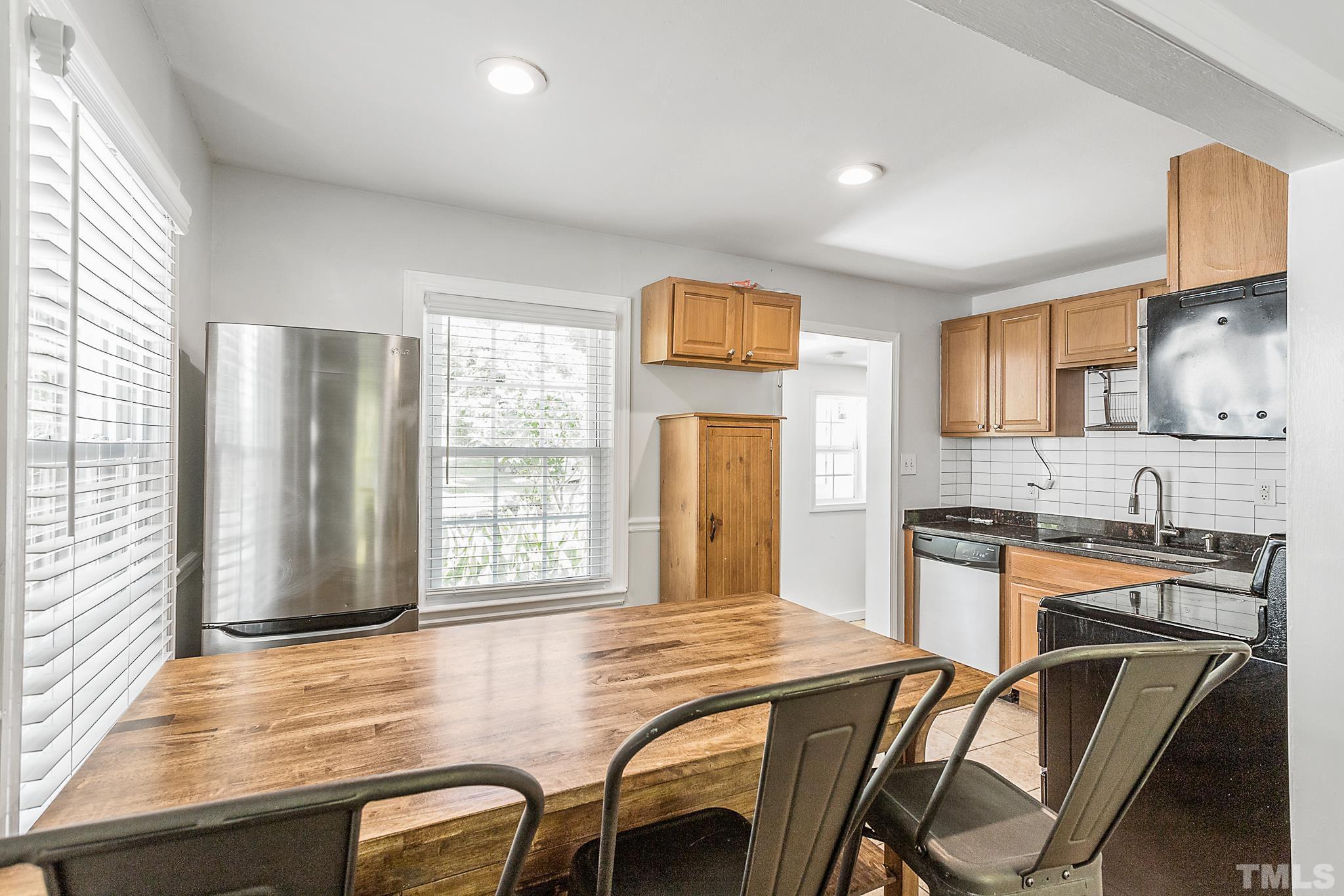 2222 Glascock Street Raleigh, NC 27610 - Photo 4 of 20 a kitchen with a table chairs refrigerator and cabinets