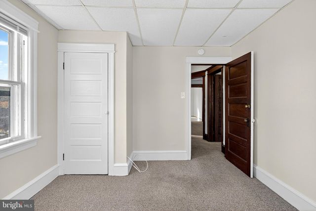 a view of an empty room with wooden floor and closet