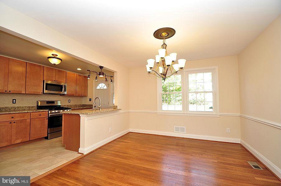 1841 Loch Shiel Road Baltimore, MD 21286 - Photo 3 of 23 a large kitchen with stainless steel appliances granite countertop a stove top oven a sink dishwasher with a dining table and chair with wooden floor