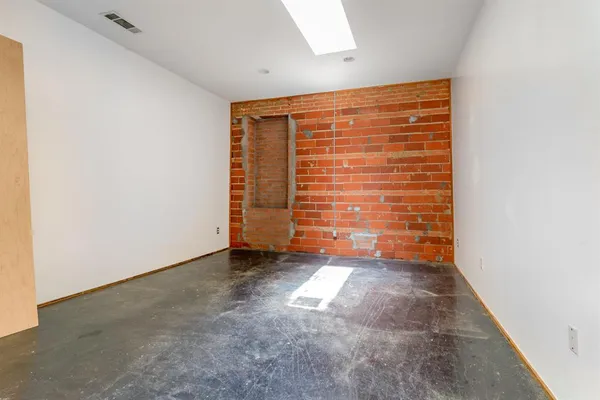 a view of an empty room with brick wall and a window