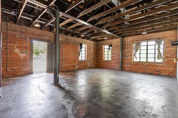 a view of an empty room with wooden floor and windows