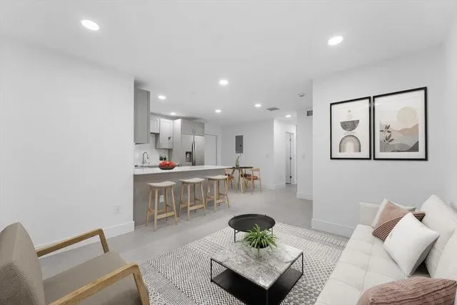 a living room with furniture and a view of kitchen