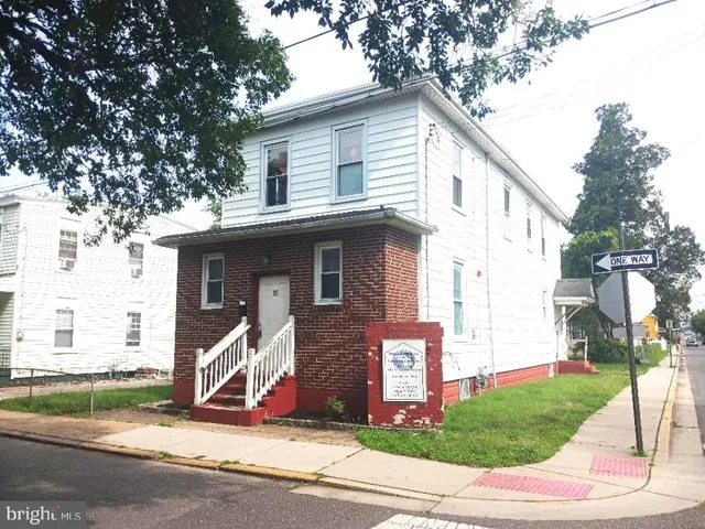 a view of a white house with a small yard and plants