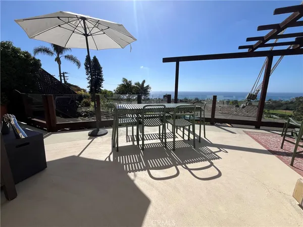 a view of a swimming pool with a patio and couches under an umbrella