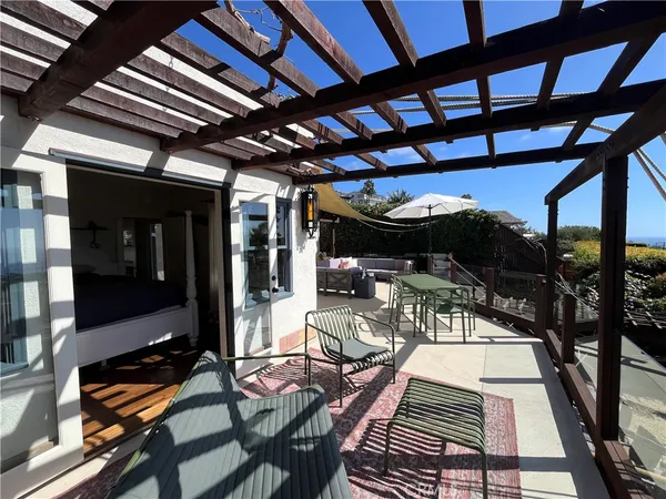 a view of a patio with table and chairs under an umbrella with a barbeque