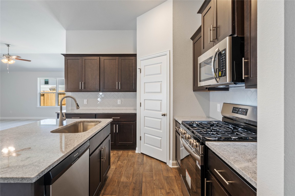 10641 Ellerston Road Cleveland, TX 77327 - Photo 14 of 34 a kitchen with granite countertop stainless steel appliances a sink stove and cabinets