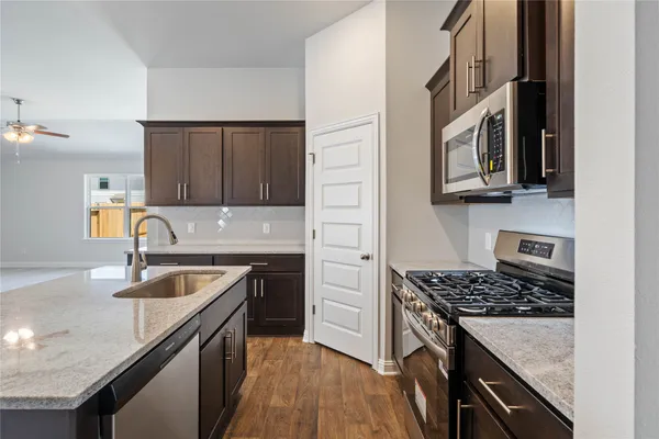 a kitchen with granite countertop stainless steel appliances a sink stove and cabinets