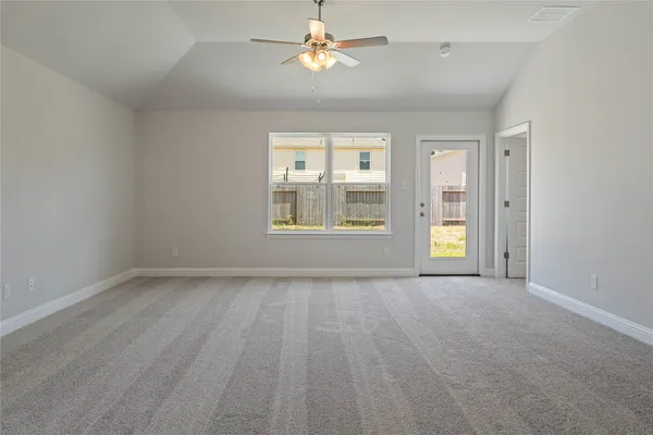 an empty room with windows and chandelier fan