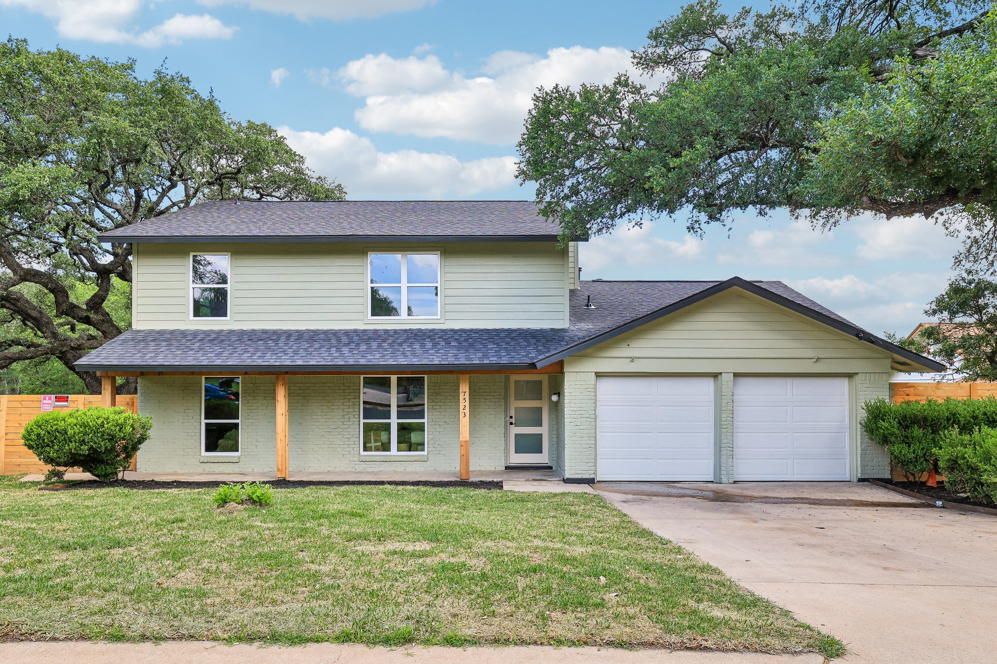7523 Glenhill Road Austin, TX 78752 - Photo 1 of 38 Green siding adorns this inviting residence, featuring a two-car garage and a classic covered porch.
