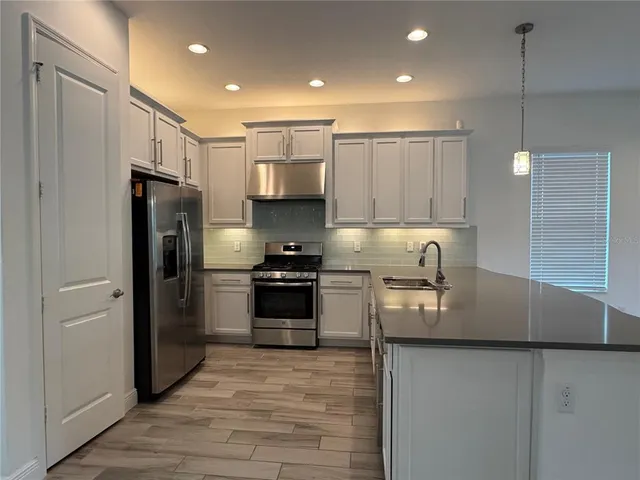 a kitchen with stainless steel appliances granite countertop a refrigerator a stove a sink and a microwave