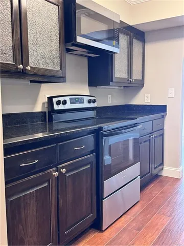 a kitchen with granite countertop wooden cabinets and a wooden floor