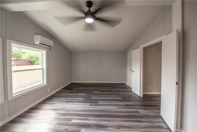 an empty room with wooden floor fan and windows