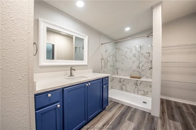 a bathroom with a granite countertop sink a mirror and shower