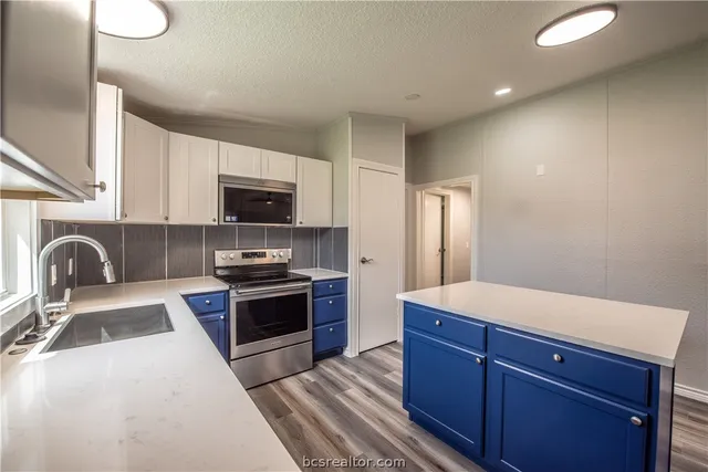 a kitchen with stainless steel appliances granite countertop a stove a sink and a microwave