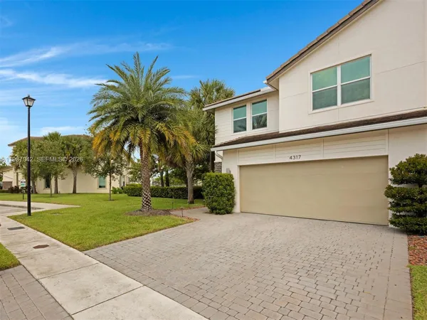 a front view of a house with a yard and palm trees
