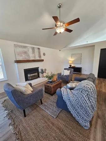 a living room with furniture a large window wooden floor and a rug