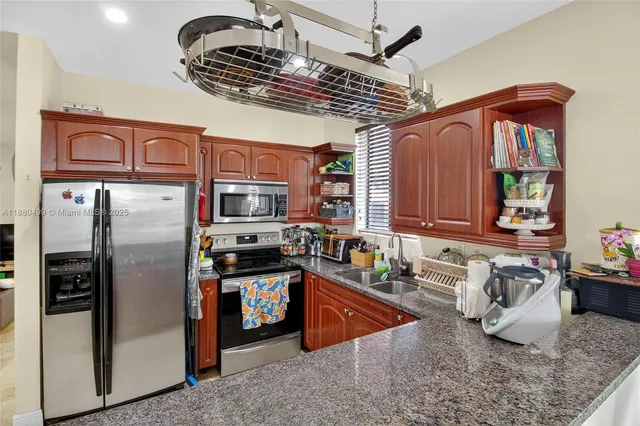 a kitchen with stainless steel appliances granite countertop a sink a stove and a refrigerator