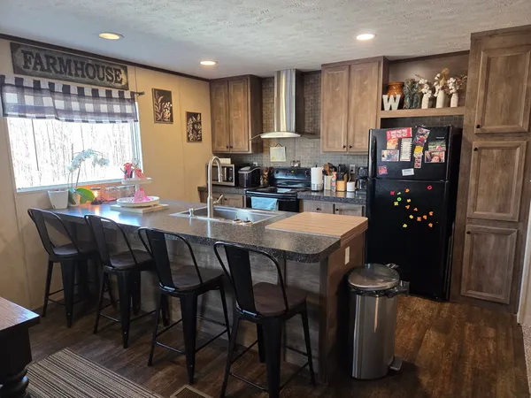 a kitchen with stainless steel appliances granite countertop a table chairs and a refrigerator