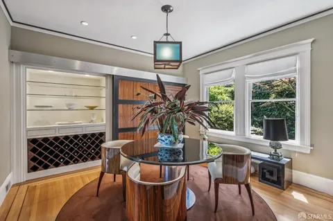 a dining room with wooden floor a chandelier a glass table and chairs