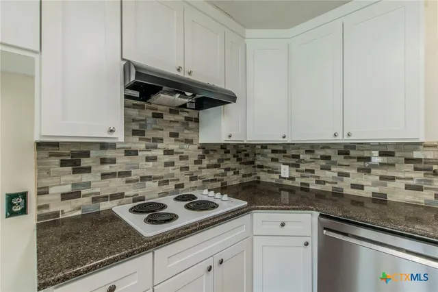 a kitchen with granite countertop a sink stove and cabinets