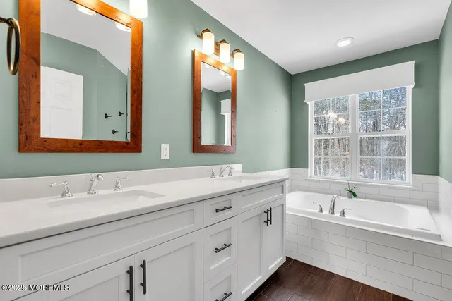 a bathroom with double vanity sinks a large mirror and a bathtub
