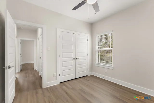 an empty room with wooden floor cabinet and windows
