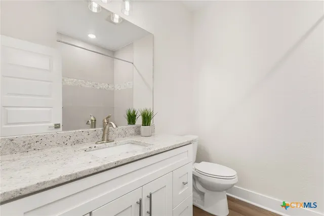 a bathroom with a granite countertop sink a toilet and mirror