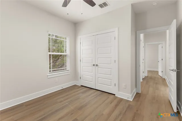 an empty room with wooden floor cabinet and windows