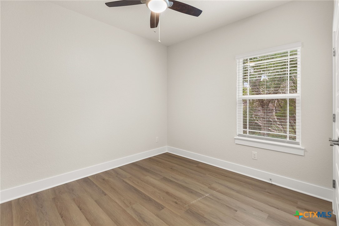 952 Rimrock Cove Spring Branch, TX 78070 - Photo 16 of 39 an empty room with wooden floor chandelier fan and windows