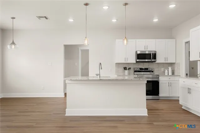 a kitchen with kitchen island a sink stainless steel appliances and cabinets