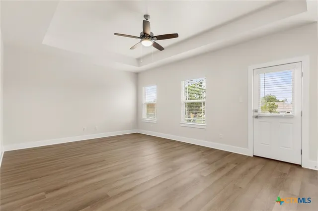 a view of an empty room with wooden floor and a window