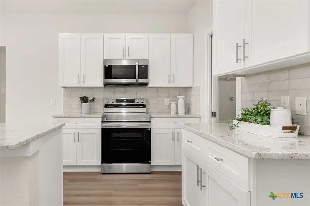 a kitchen with white cabinets stainless steel appliances and a potted plant