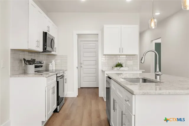 a kitchen with stainless steel appliances granite countertop a sink stove and refrigerator