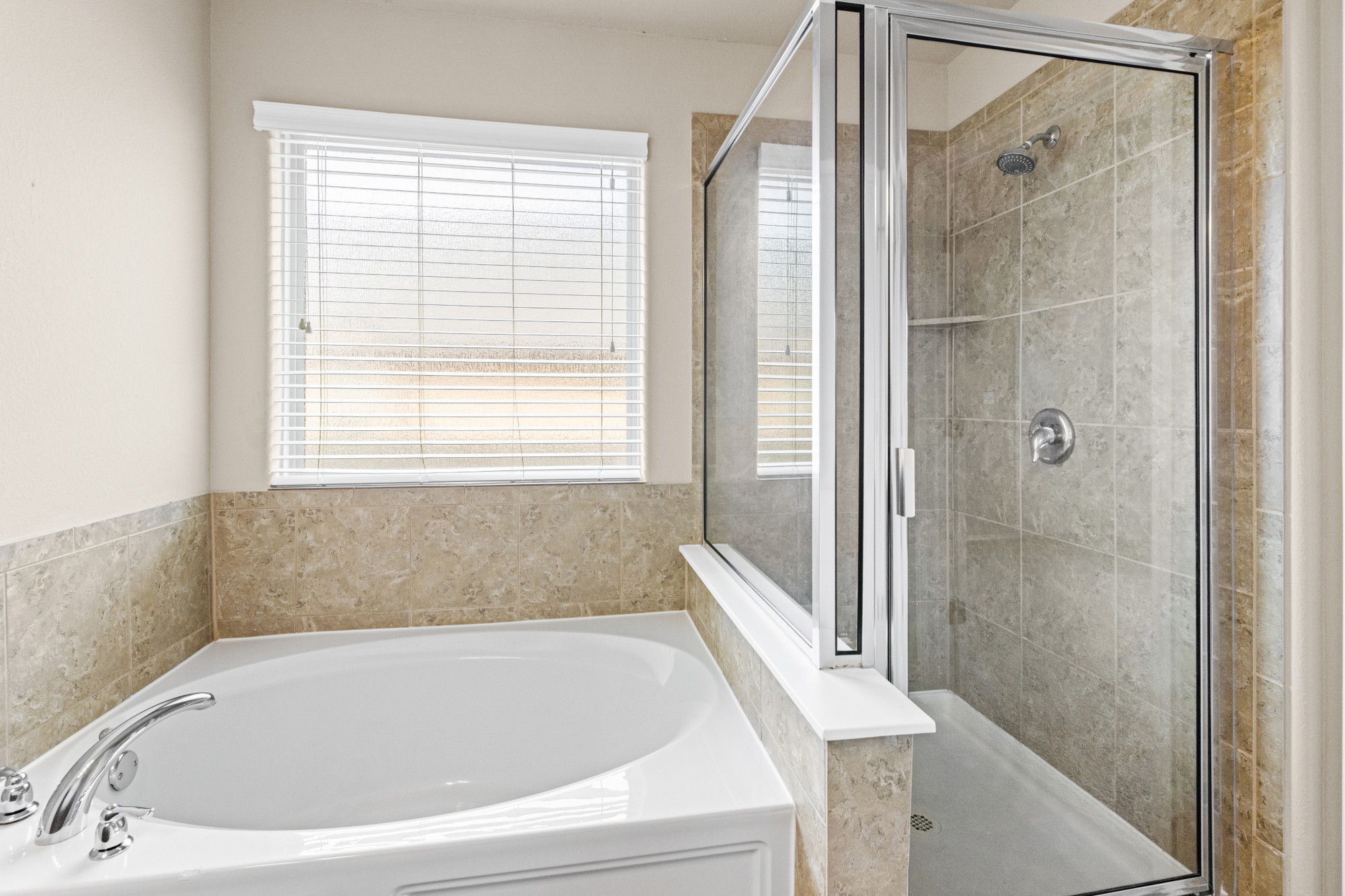 19308 Stokes Lane Pflugerville, TX 78660 - Photo 12 of 27 Spacious bathroom featuring a built-in soaking tub with polished chrome fixtures, a separate shower enclosure with glass panels, and tile surrounds
