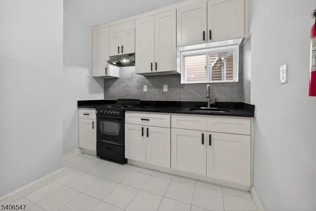 a kitchen with granite countertop white cabinets and sink