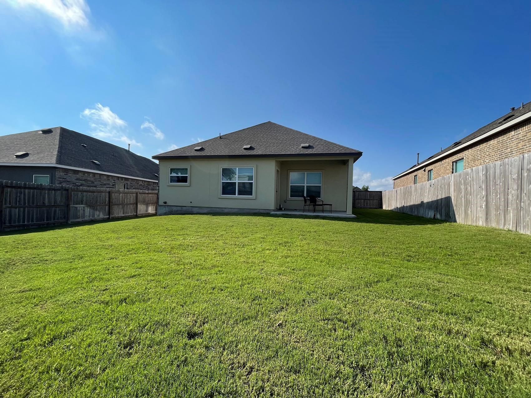 1625 Woolsey Way Leander, TX 78641 - Photo 16 of 17 The property features a spacious rear yard with a well-maintained lawn and a privacy fence