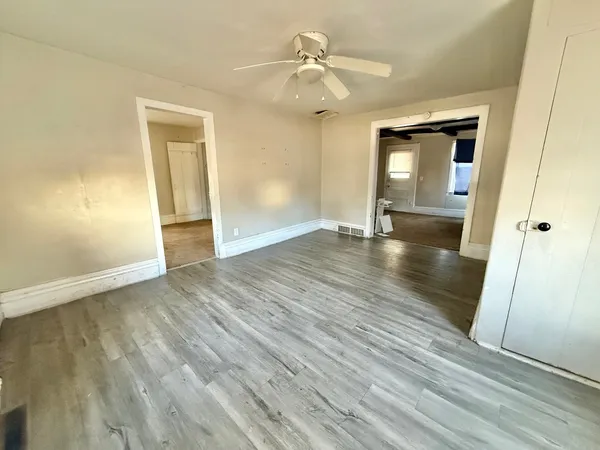 a view of empty room with wooden floor and fan