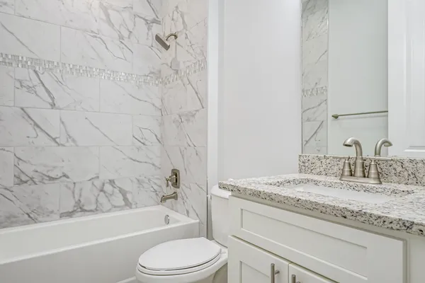 a bathroom with a granite countertop sink toilet and bathtub
