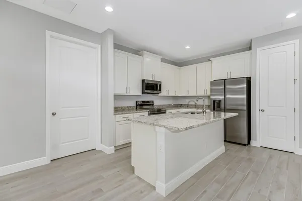 a kitchen with a sink a refrigerator a microwave and cabinets