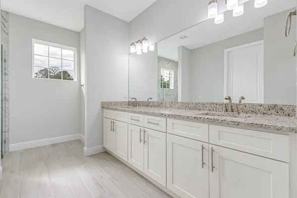 a bathroom with a granite countertop double vanity sink and mirror
