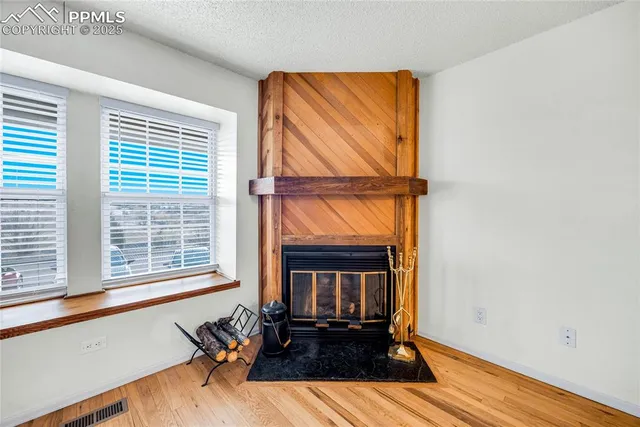 a view of an empty room with wooden floor fireplace and a window