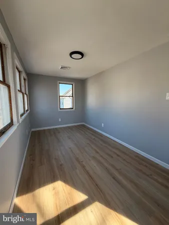 a view of an empty room with wooden floor and windows