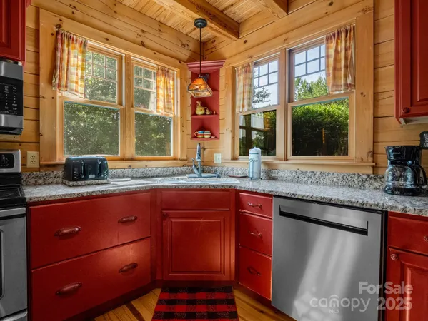 a kitchen with stainless steel appliances granite countertop wooden cabinets a sink and a large window