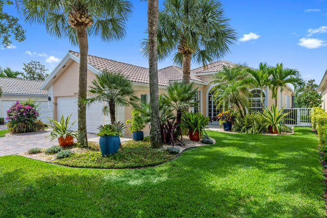 a view of a house with a yard and palm trees