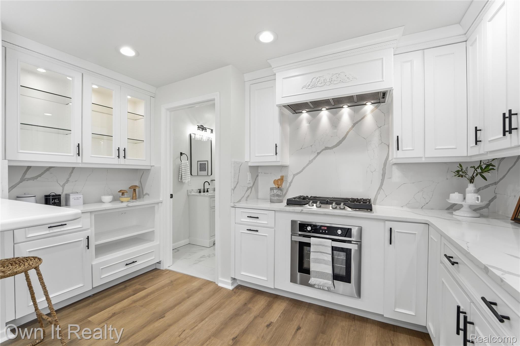 168 Kerby Road Grosse Pointe, MI 48236 - Photo 8 of 36 White cabinetry, white countertops with veining, stainless steel gas range, integrated double oven, and wood-finish flooring