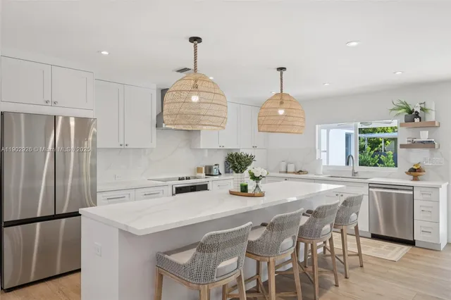 a kitchen with stainless steel appliances a sink a stove a refrigerator and white cabinets