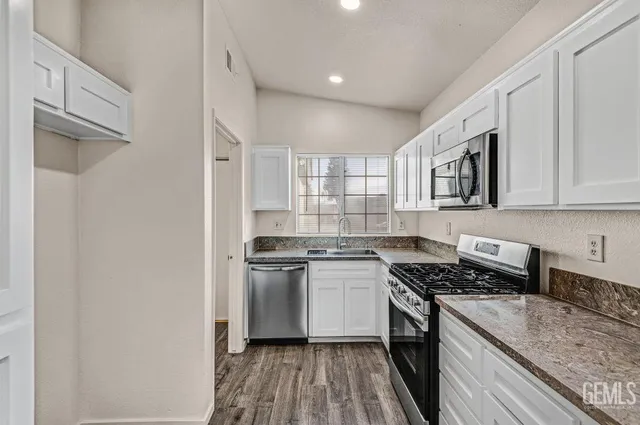 a kitchen with stainless steel appliances granite countertop a stove a sink and a refrigerator