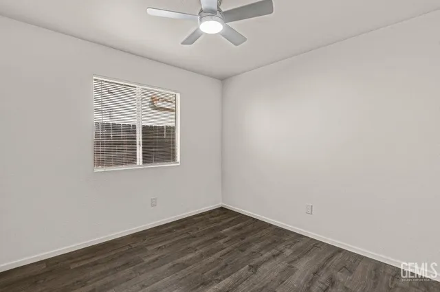 an empty room with wooden floor chandelier fan and windows